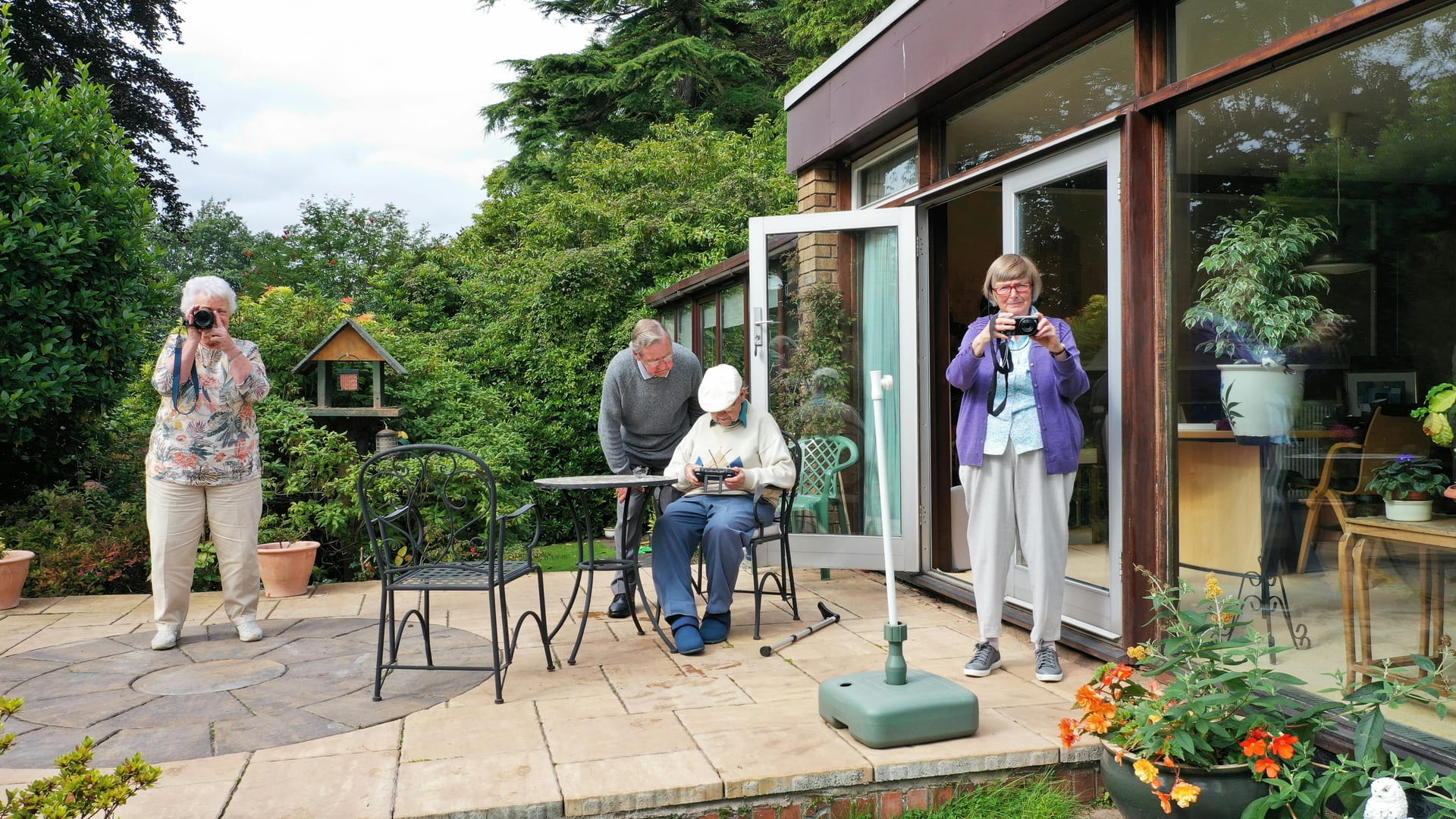 A group of seniors together on a garden patio outside their home